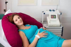 Беременная женщина лежит в кабинете, еще не поздно рожать. 
